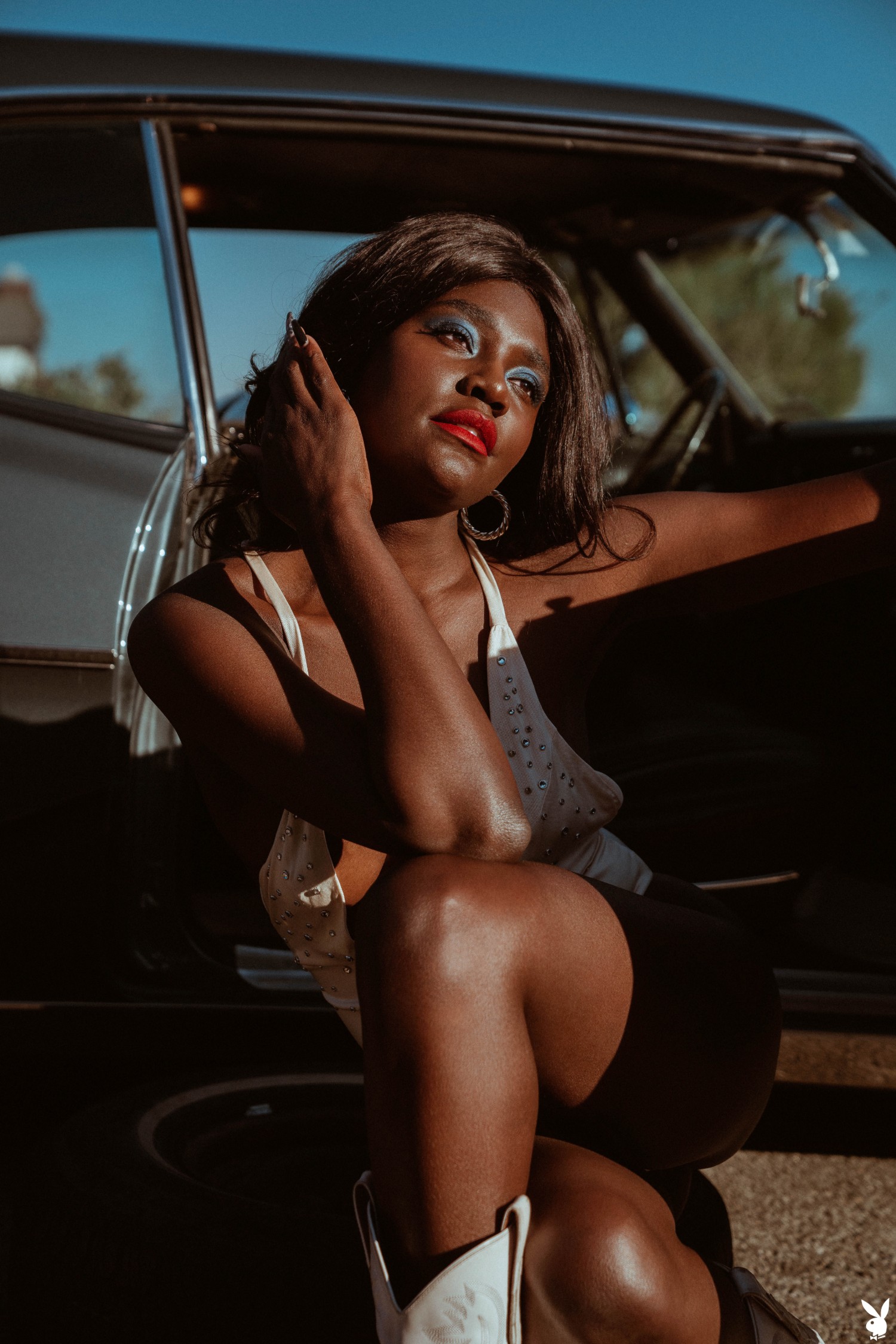 Victoria Antoinette Poses Topless In White Bodysuit Beside Vintage Car Under Blue Sky Hills