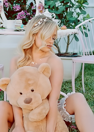Jackie in lace lingerie poses solo on garden grass, teasing with bare skin and sweet treats