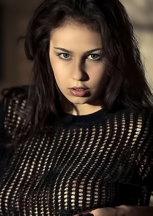 Sophie Limma kneels on the bed in sheer black top and lace underwear, caught in shadow play by the window